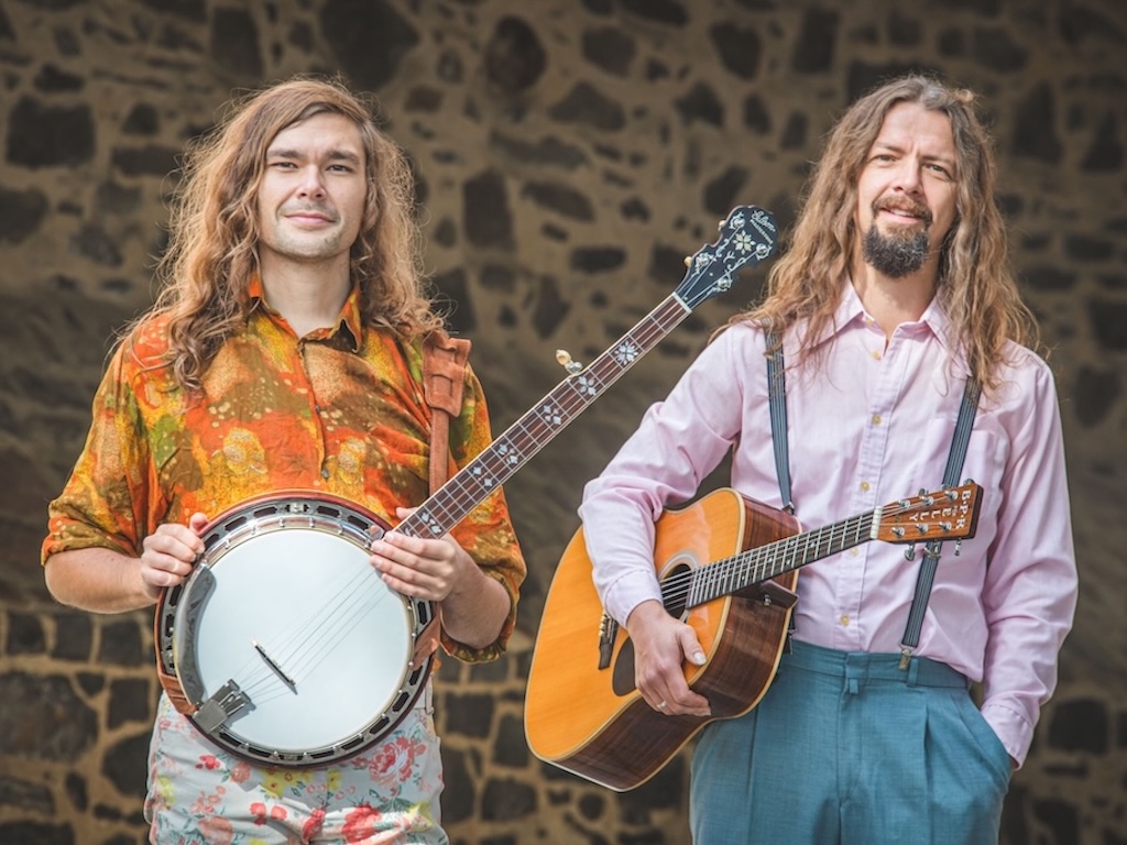 Beni Feldmann und Steffen Thede stehen mit ihren Instrumenten vor einer Steinmauer